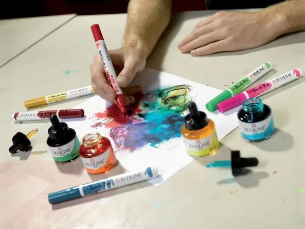 Čovjek drži akvarel marker te radi na slici. Još su i tuševi